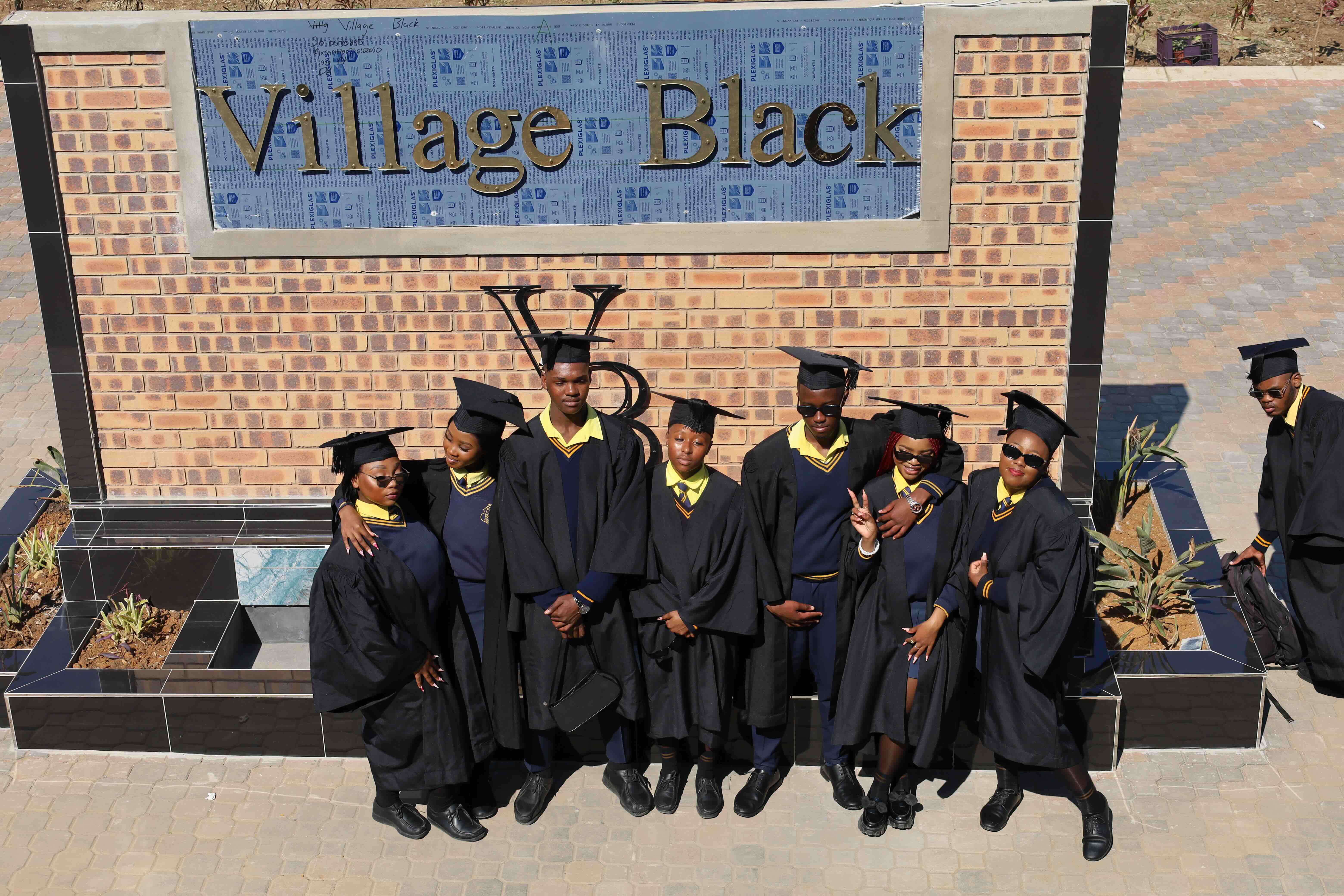 Matric graduates at the Village Black sign